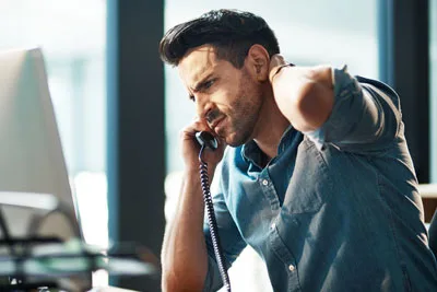 Man on the phone rubbing his neck